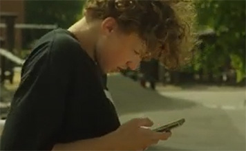 teenagedreng kigger på sin mobiltelefon